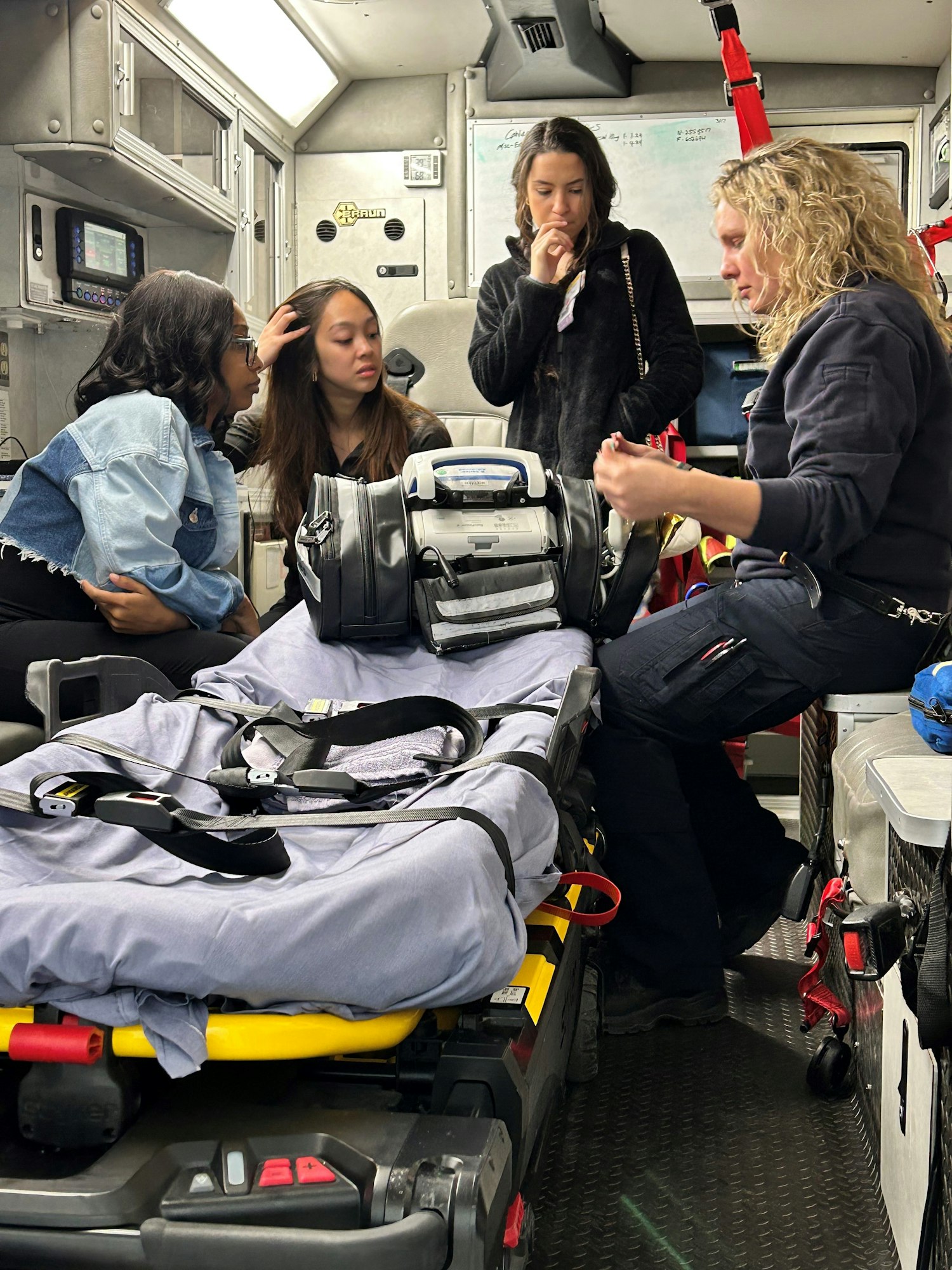 Three individuals inside an ambulance, with medical equipment and a stretcher visible.