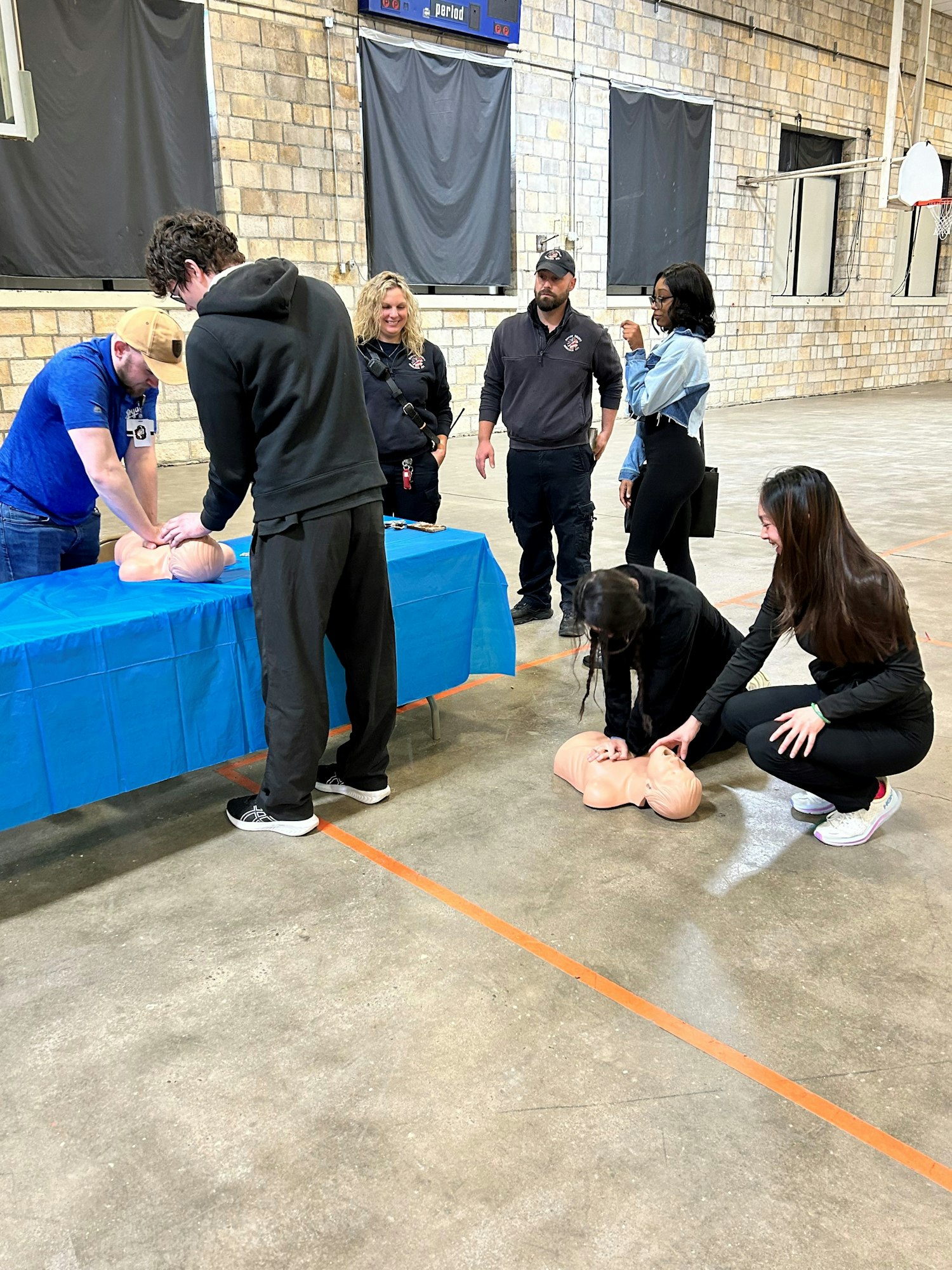 CPR training session with instructors and participants practicing on mannequins.