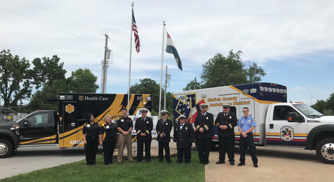 Ambulance staff posing in front of emergency vehicles