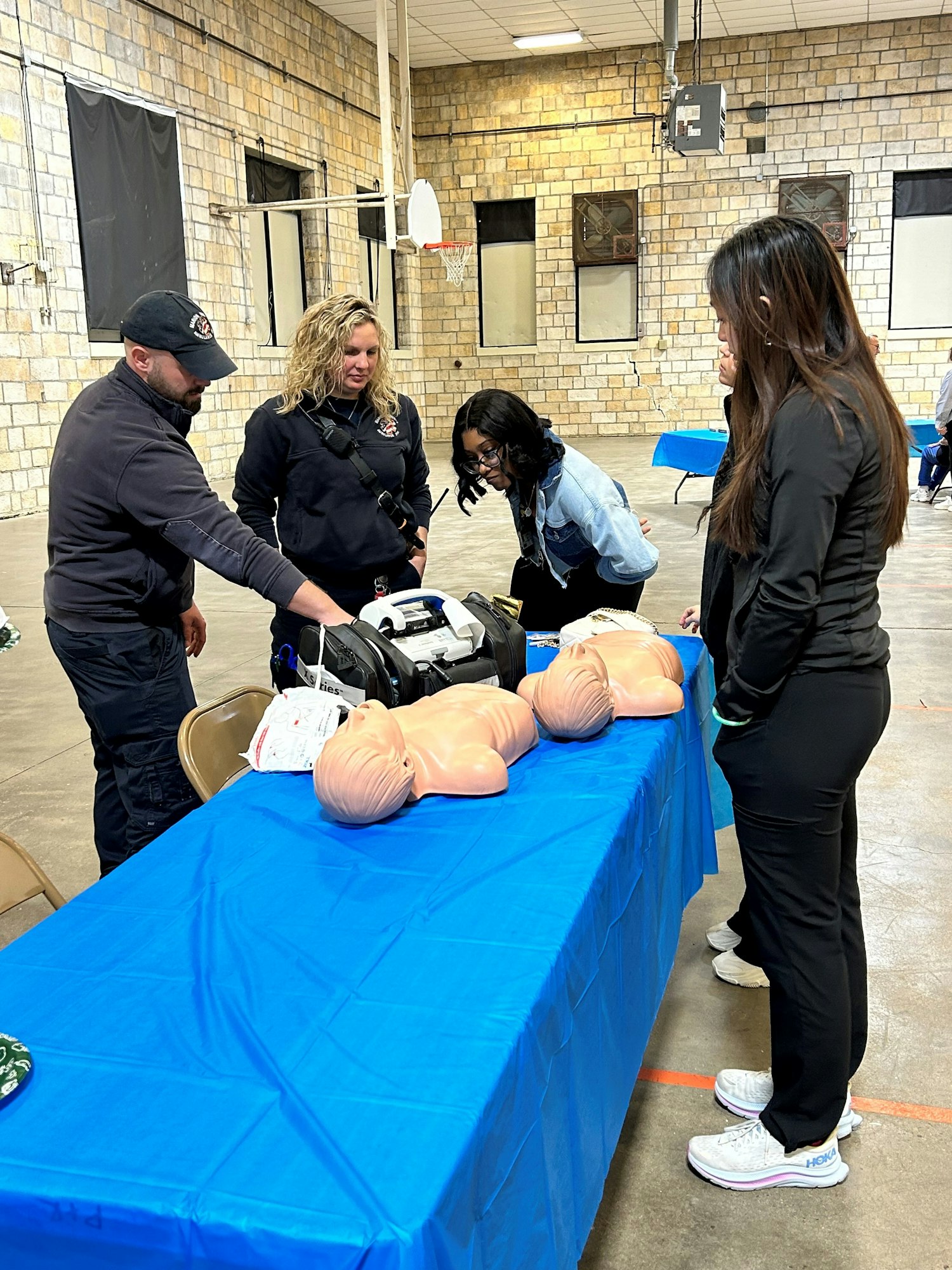 People looking at medical equipment and mannequins, possibly a CPR training session.