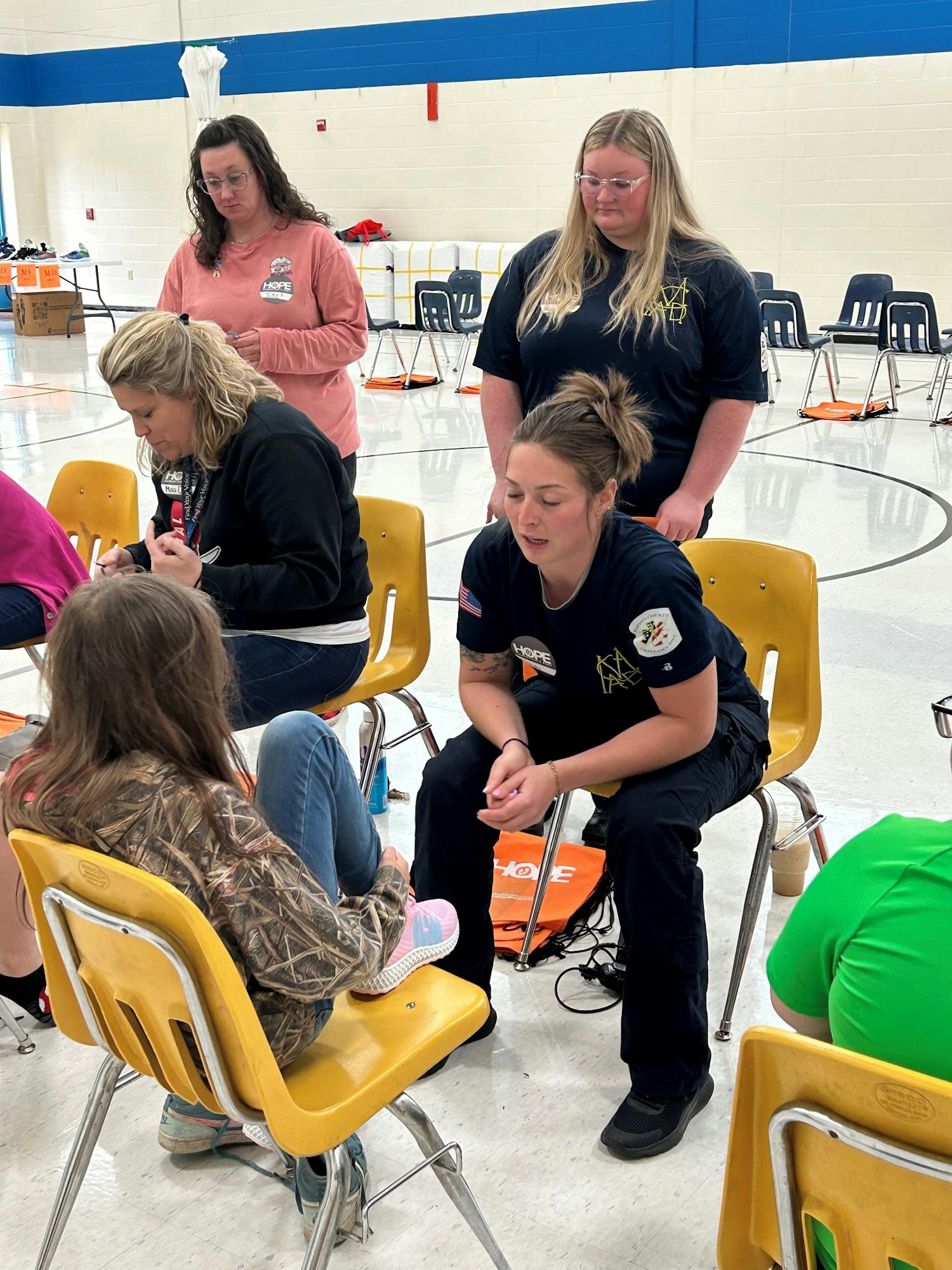 An indoor setting with adults, some in casual clothing and one in a uniform, focused on a seated activity, possibly educational or health-related.