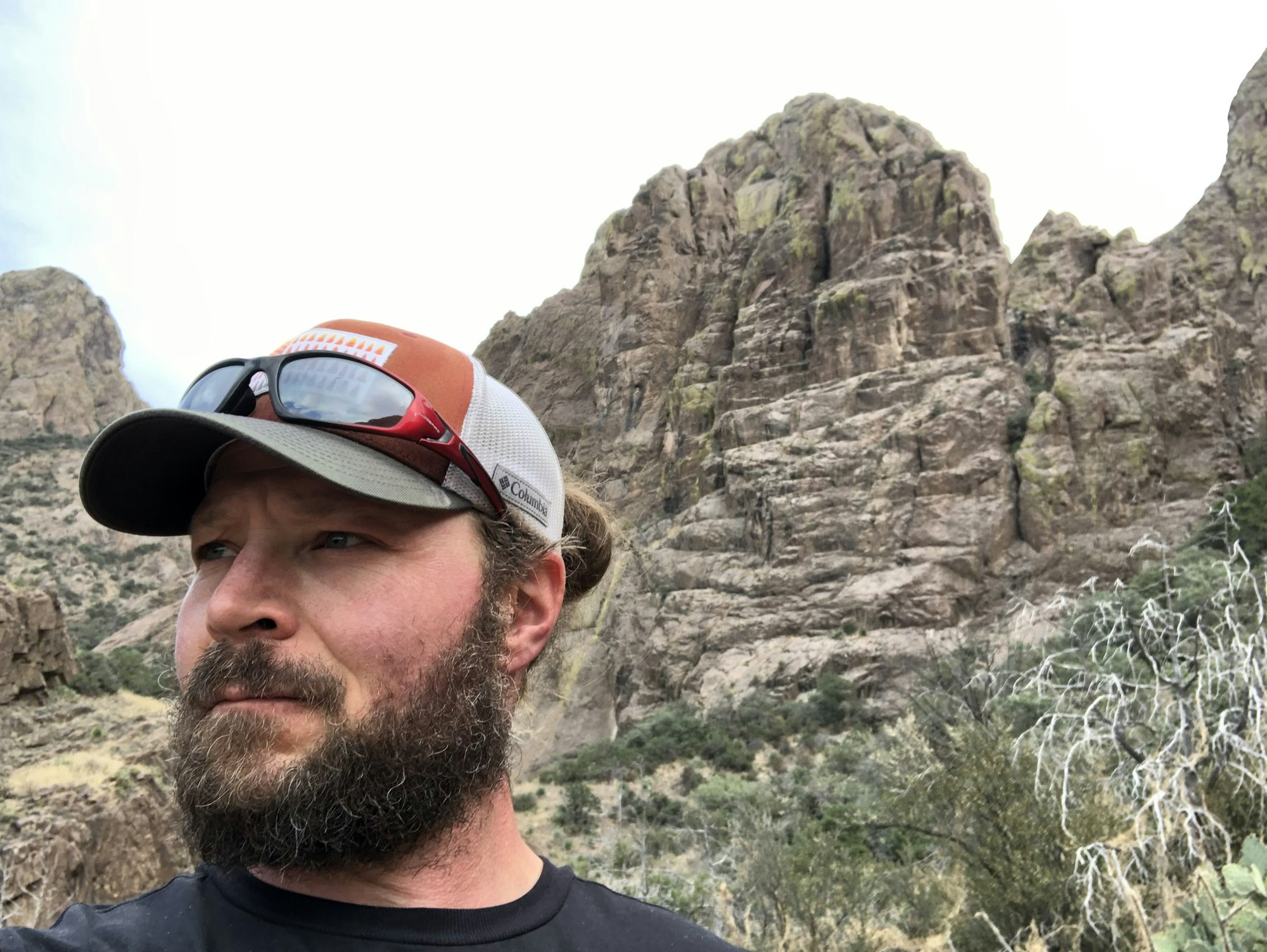 Matt wearing a cap and sunglasses in front of a rocky mountain landscape.