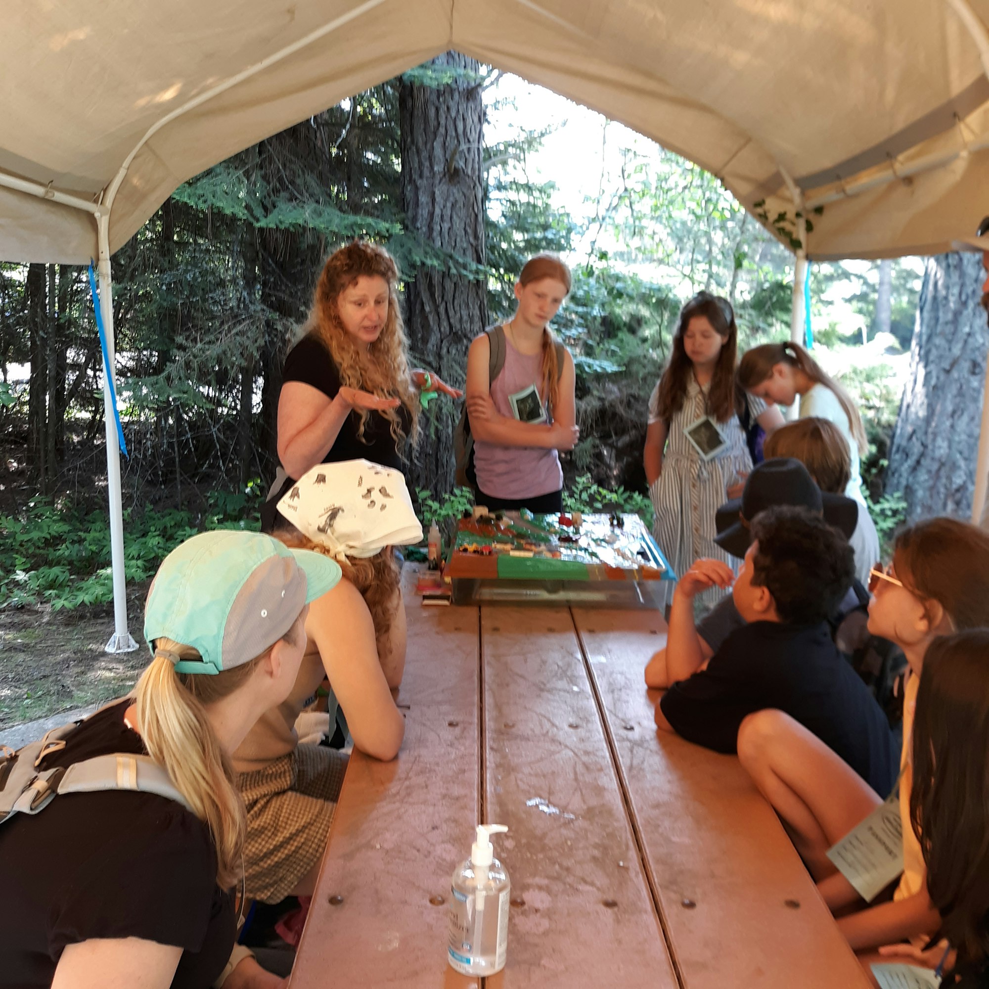 People inside a tent structure participating in an activity, with nature visible in the background.