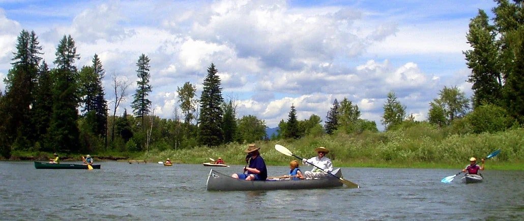 May contain: people paddling across a body of water with canoes and kayaks