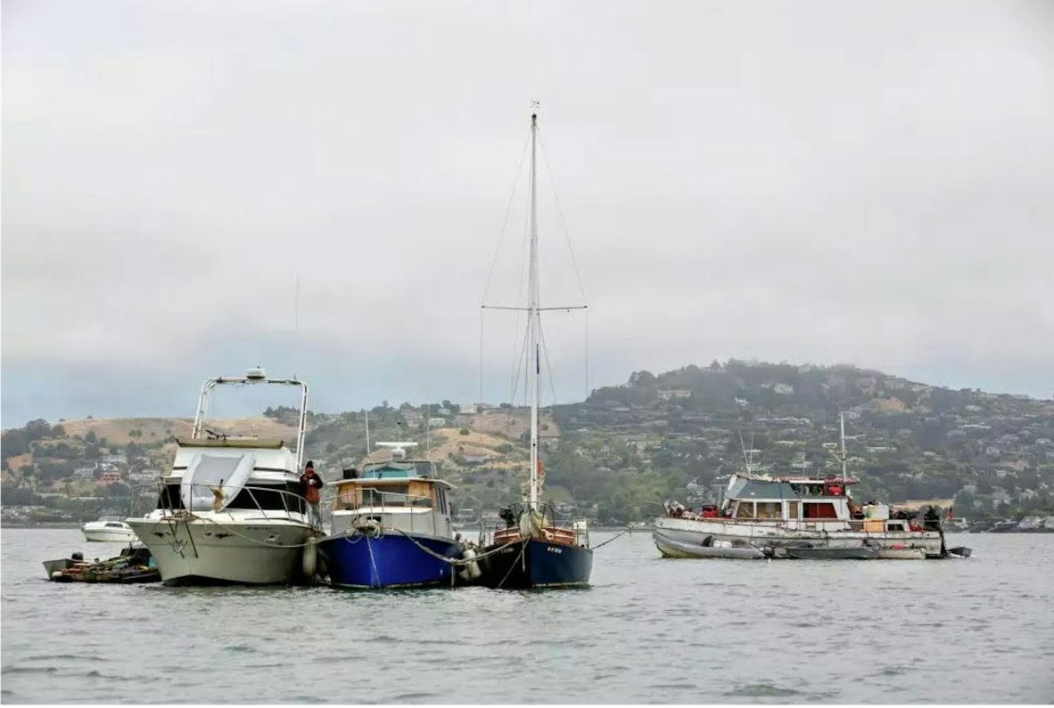 Boats on the water with hills in the background, overcast sky.