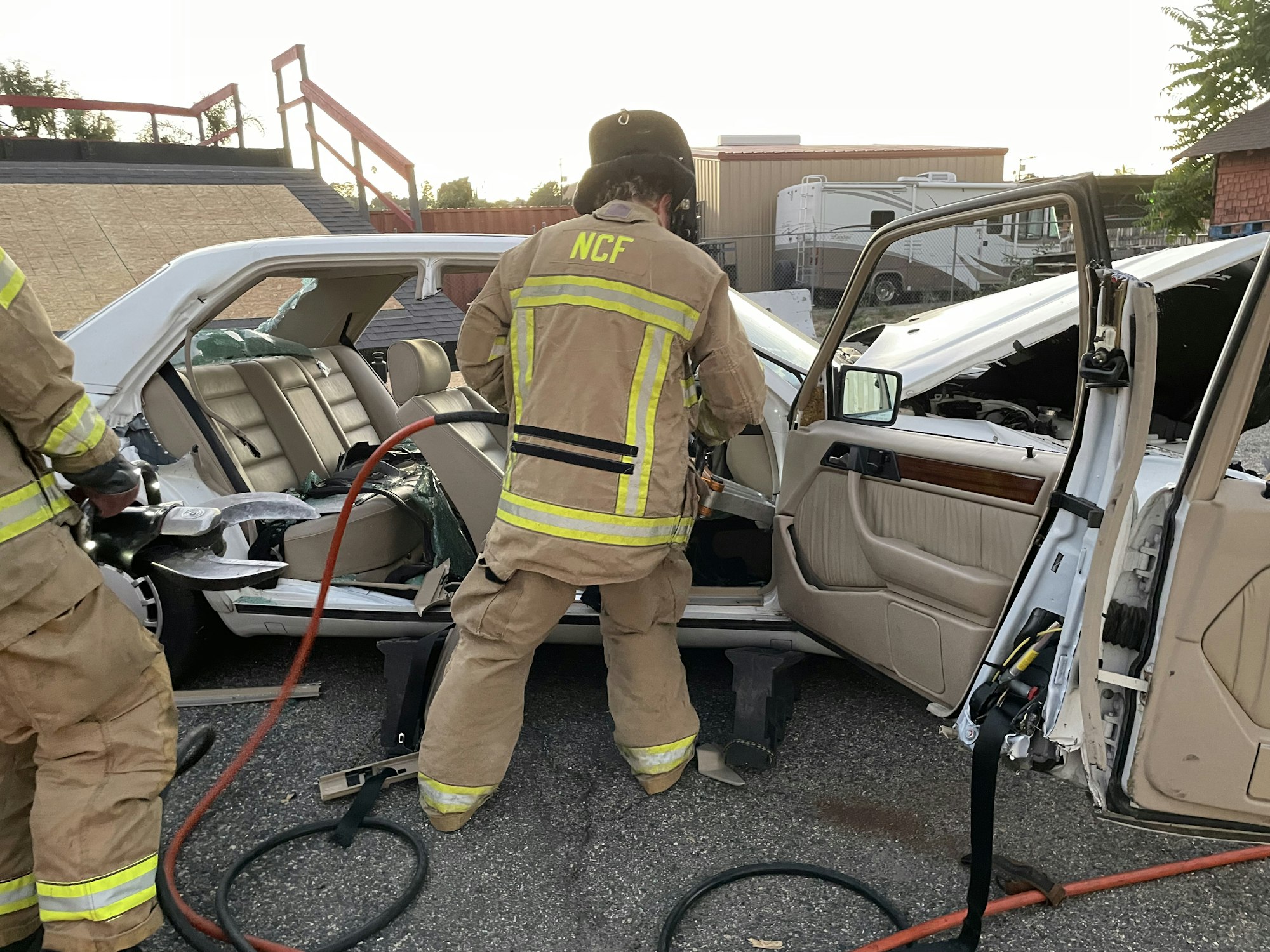 Firefighters using rescue tools on a heavily damaged car in a training or real-life extraction.
