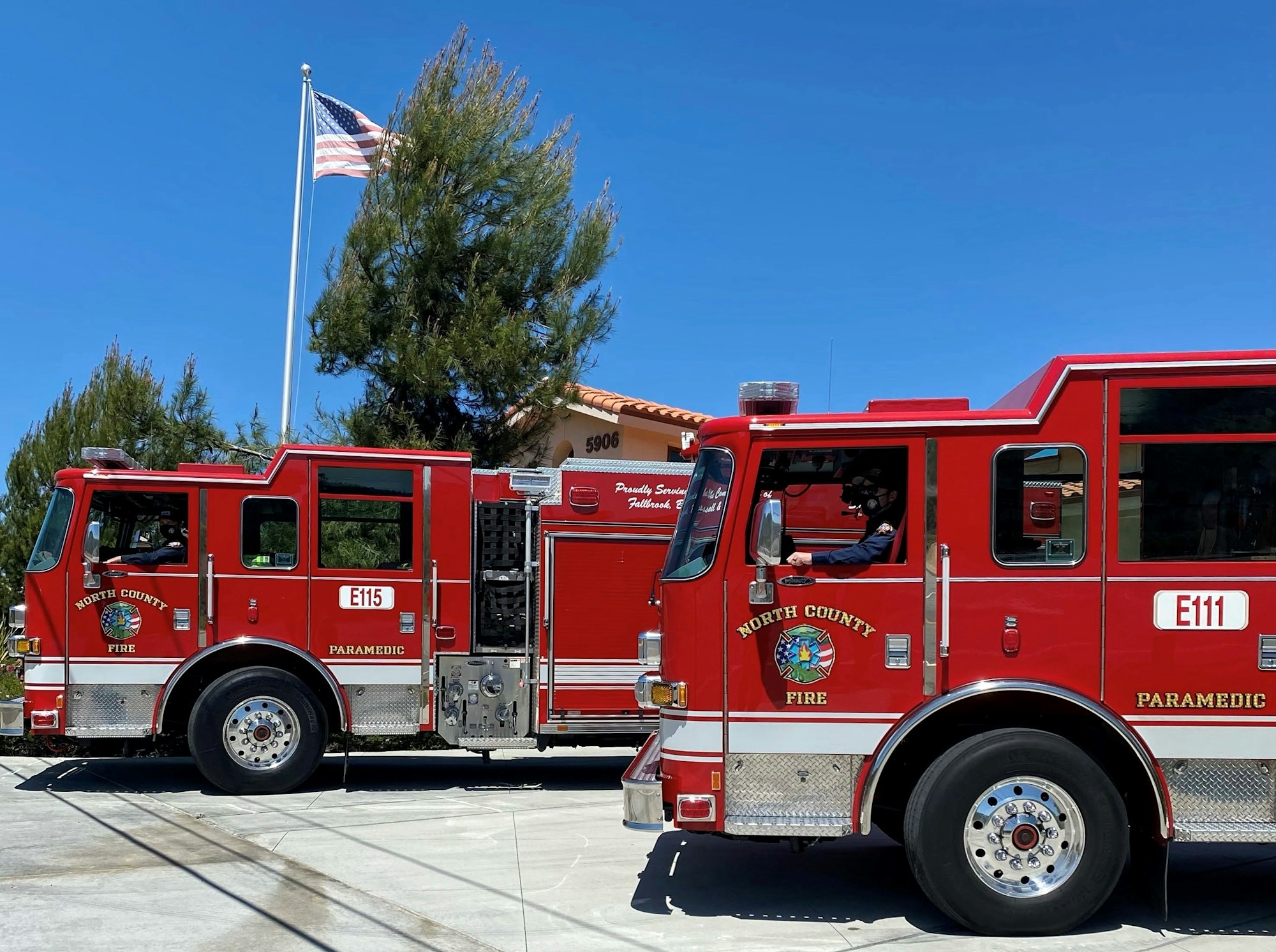 Two red fire trucks labeled "North County Fire" with American flag in the background.