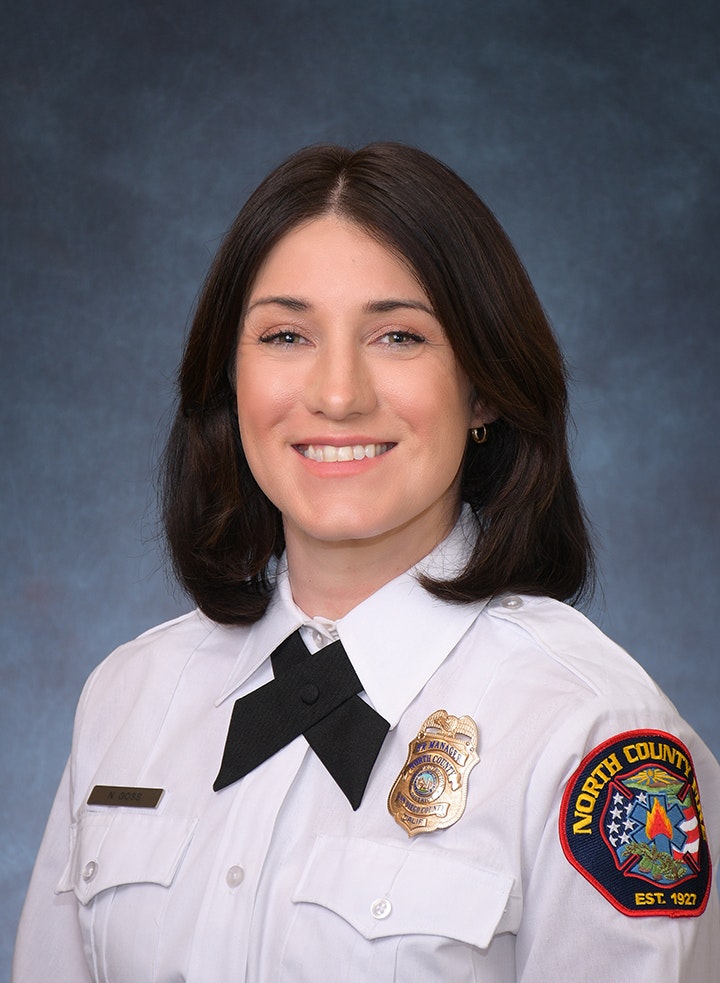 A person in a police uniform with badges and a patch reading "North County."