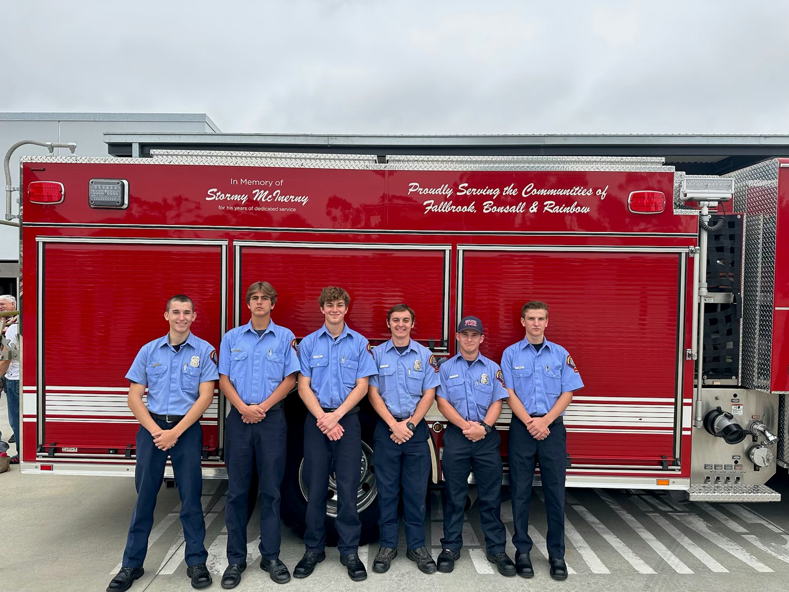 six people standing in front of a fire truck outside