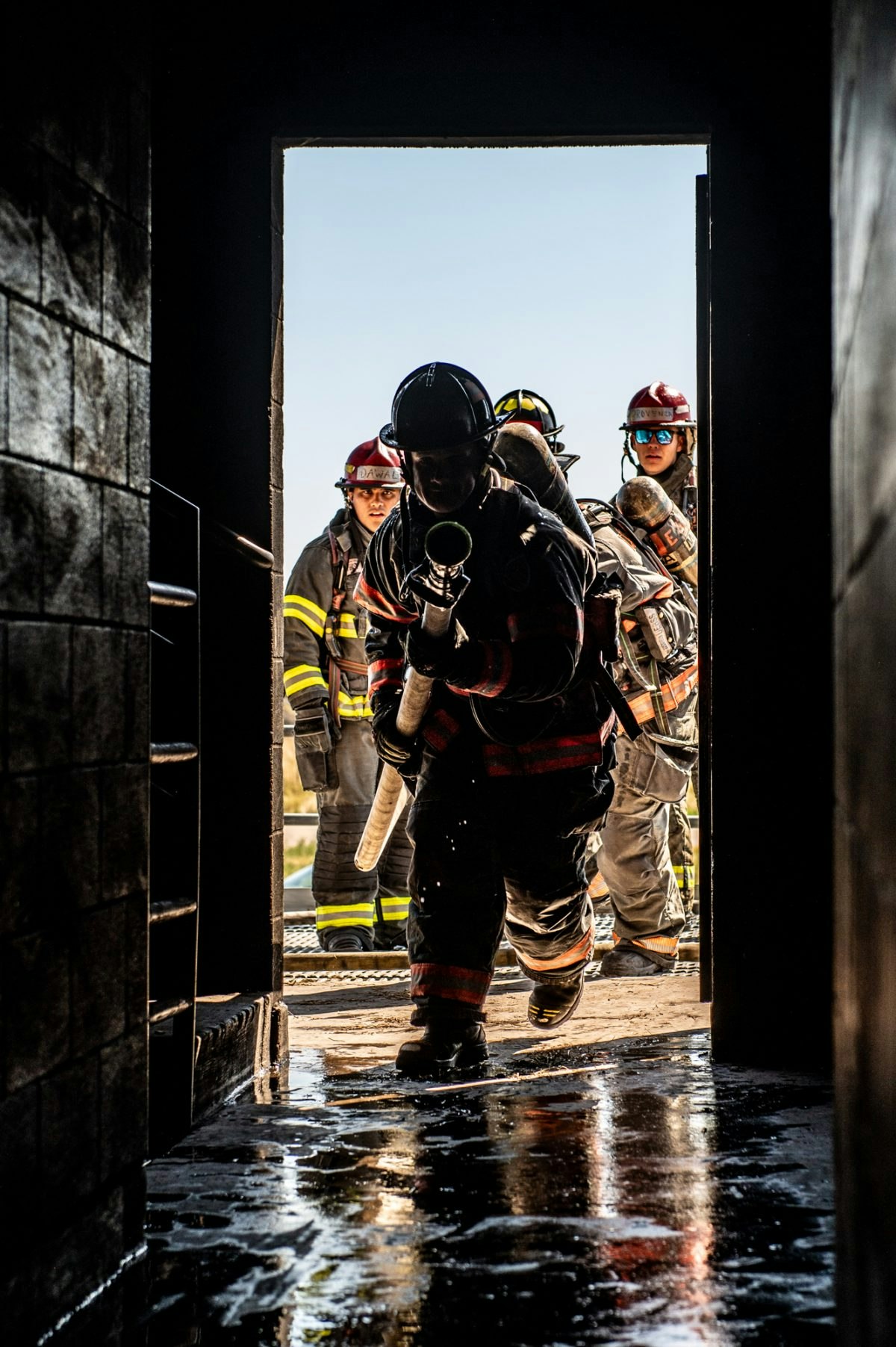 Firefighters entering a building with hoses and equipment.