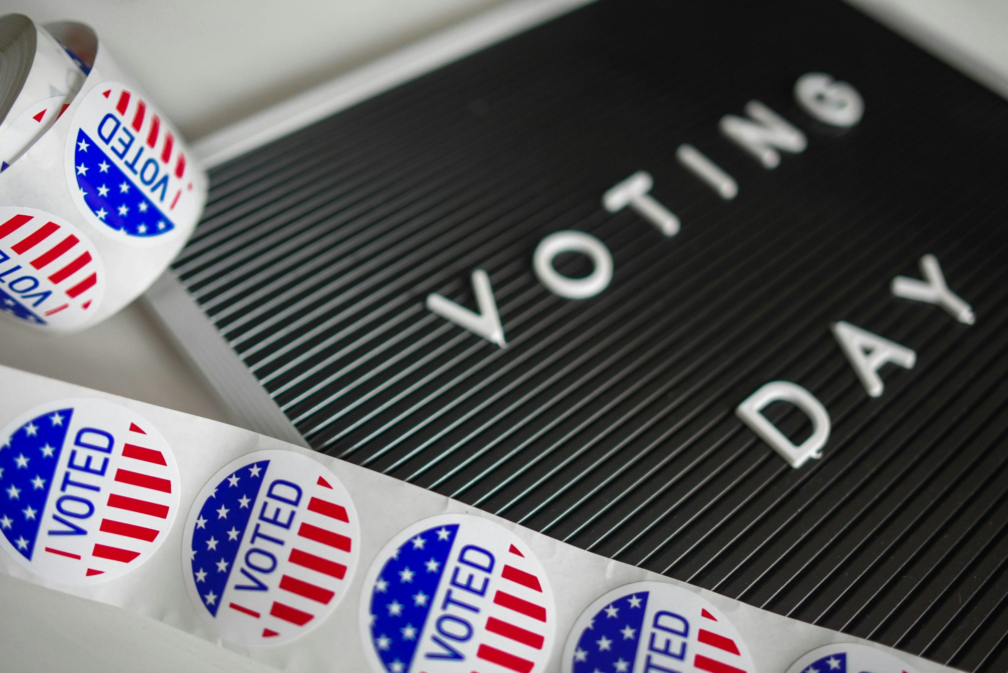 "VOTING DAY" sign with "I VOTED" stickers featuring U.S. flag design.