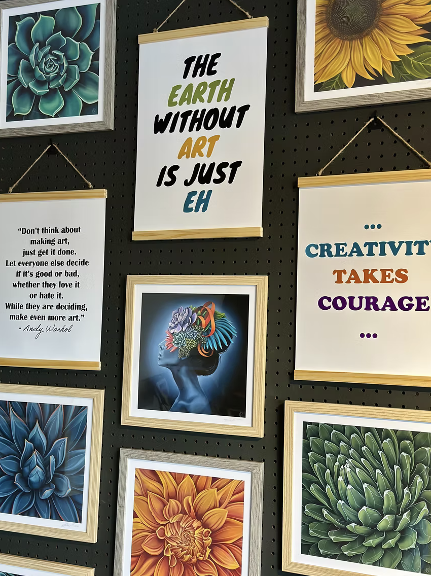Various framed quotes and floral artworks on a wall, including "The earth without art is just eh" and "Creativity takes courage."