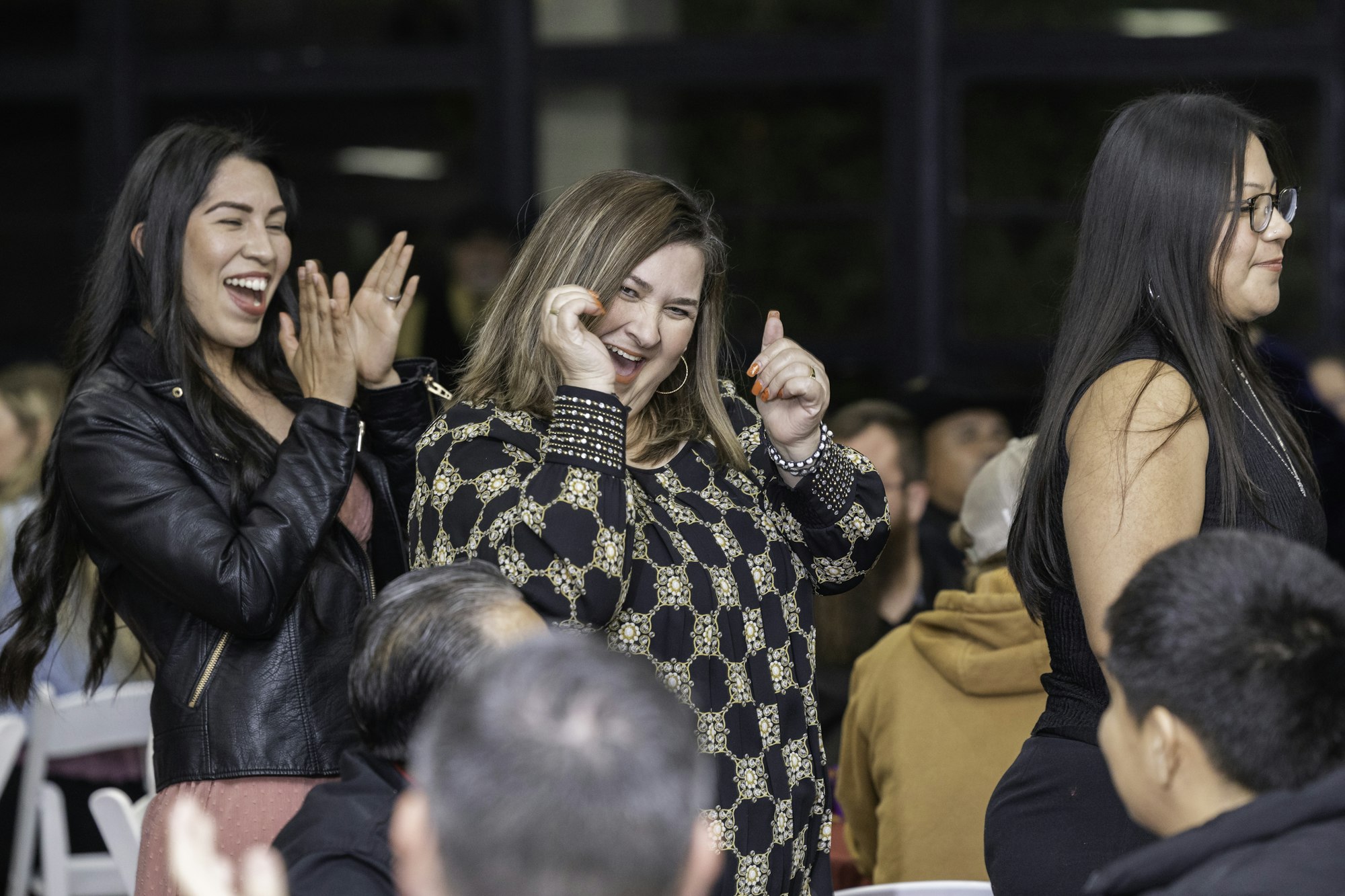 A group of people laughing and clapping at an event, creating a joyful atmosphere.