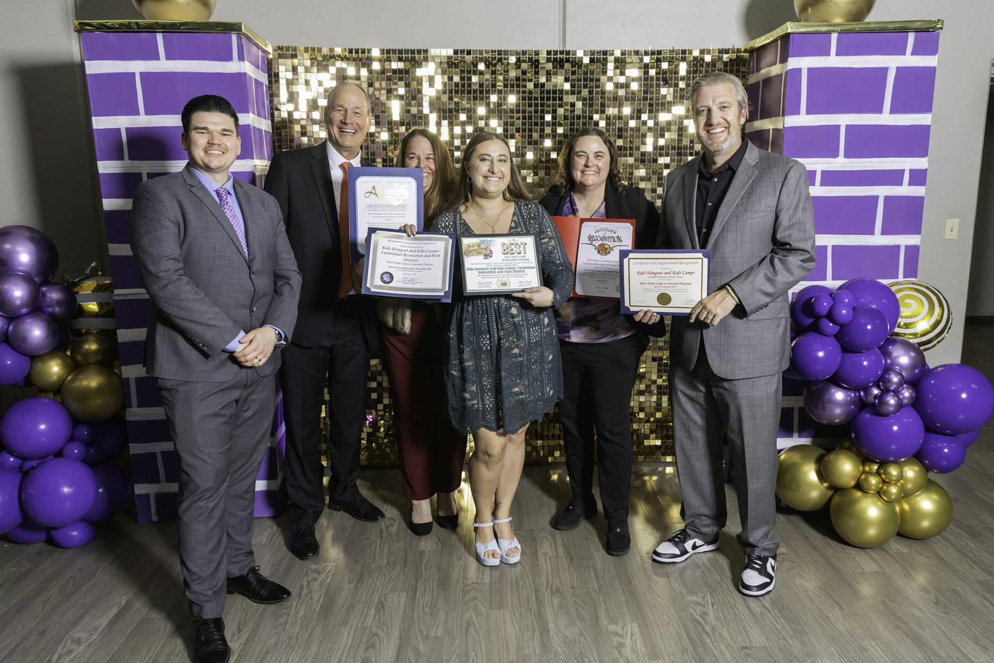 May contain: groupshot, person, clothing, footwear, shoe, people, adult, male, man, female, woman, accessories, jewelry, necklace, formal wear, tie, purple, balloon, and high heel