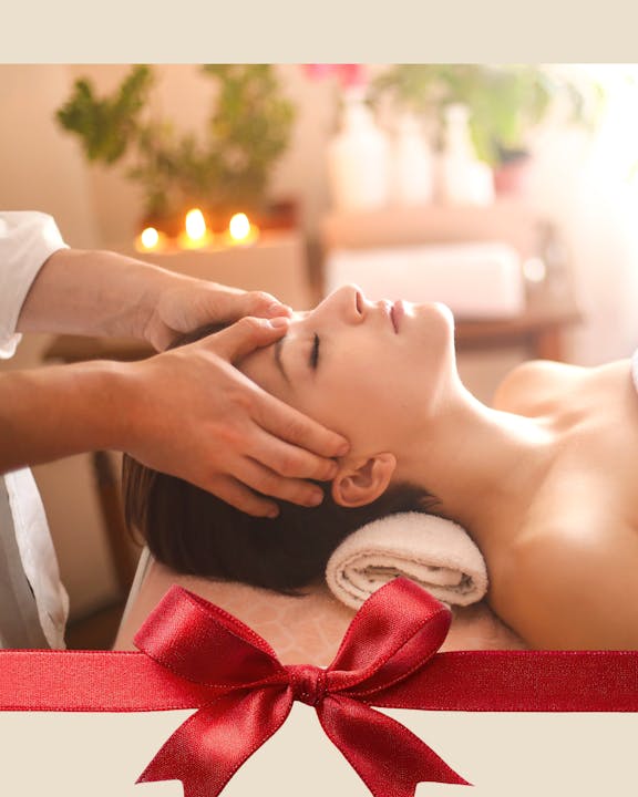 A calming spa scene featuring a person receiving a facial massage, with warm lighting and a decorative bow at the bottom.