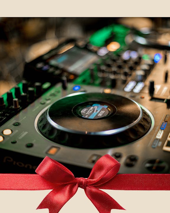 The image features a close-up of a DJ controller with a festive red bow, suggesting a gift for music lovers or DJs.