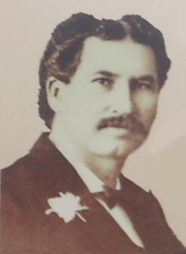 Vintage portrait of a mustachioed man with a flower on his lapel.