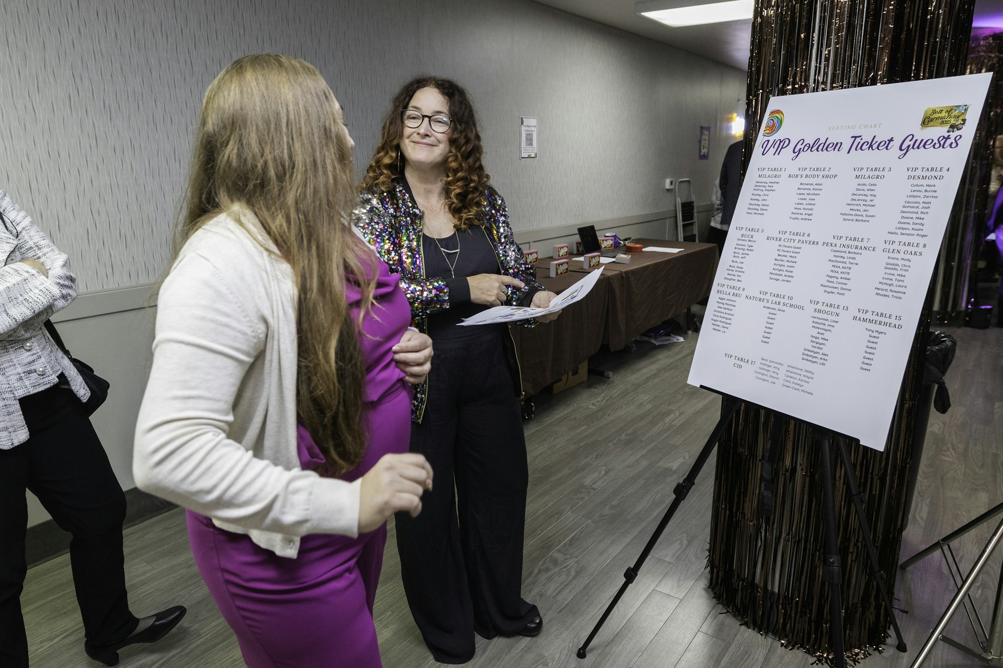 Two people are discussing a seating chart for VIP Golden Ticket Guests at an event.