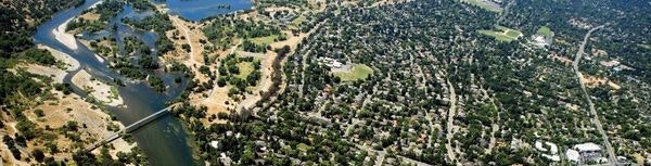 Aerial view of a river meandering through a green landscape with trees and houses.