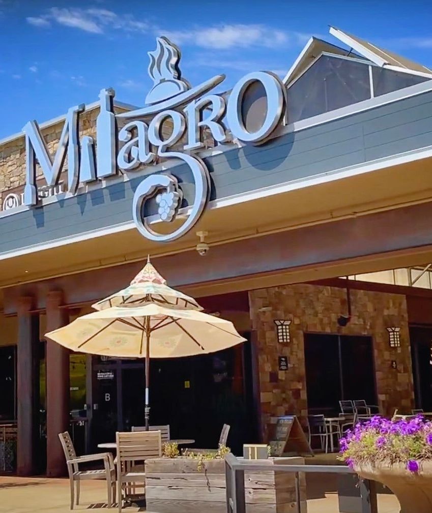 A restaurant called Milagro with outdoor seating and an umbrella.