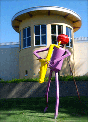 Colorful abstract sculpture of a figure holding a saxophone, in front of a building with a round tower.
