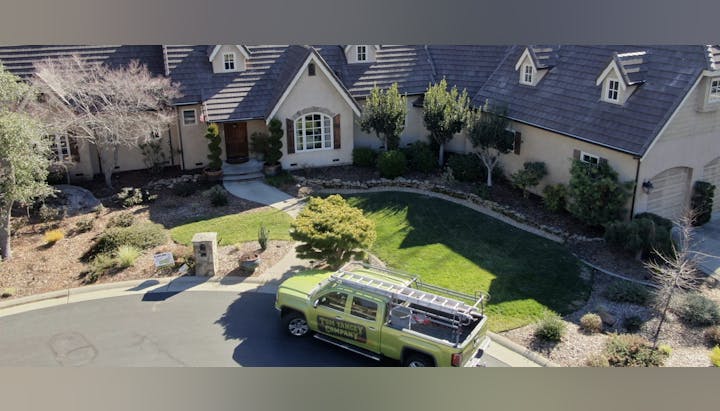 House with a well-kept garden, trees, and a truck labeled "Tom Yancey Company" parked on the street.