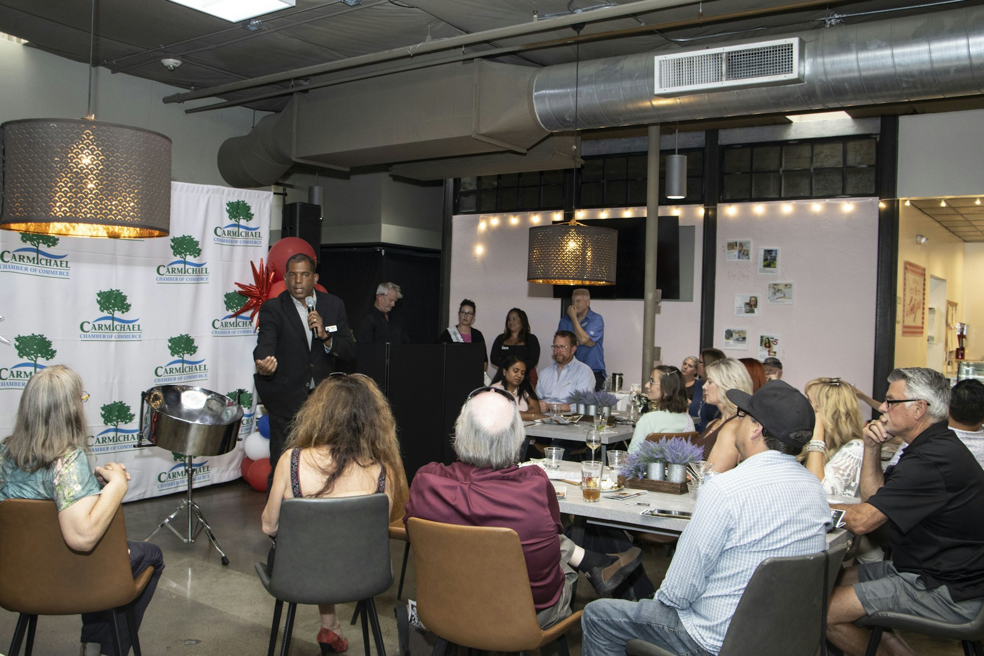 A person speaks to a seated audience at a Carmichael Chamber of Commerce event.