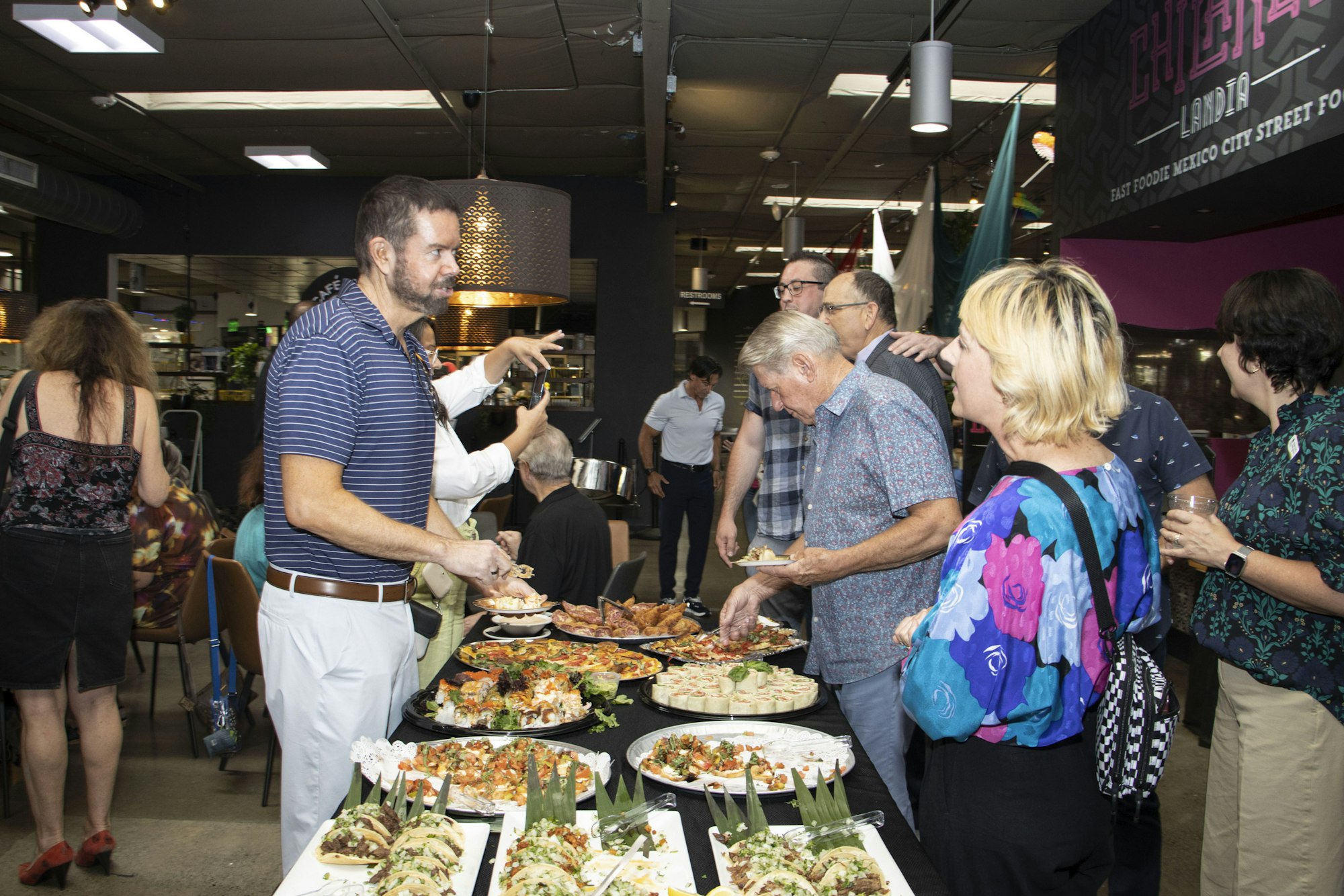 People enjoying a buffet with various dishes in a casual indoor setting.