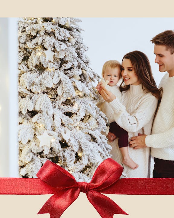 A family decorates a snowy Christmas tree together, creating a festive and warm holiday atmosphere.
