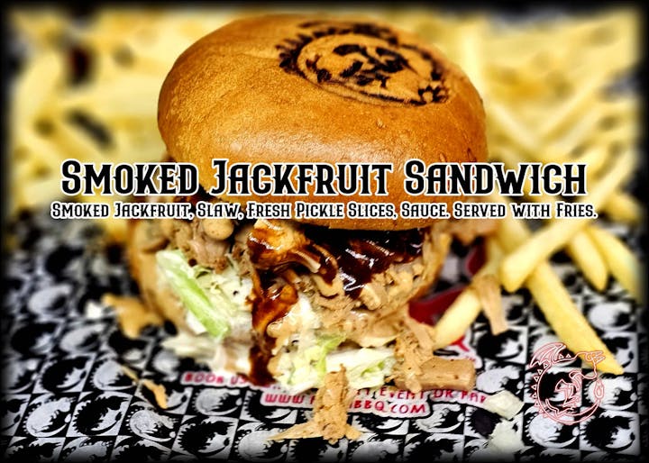 Smoked jackfruit sandwich with slaw, pickles, sauce, and fries.