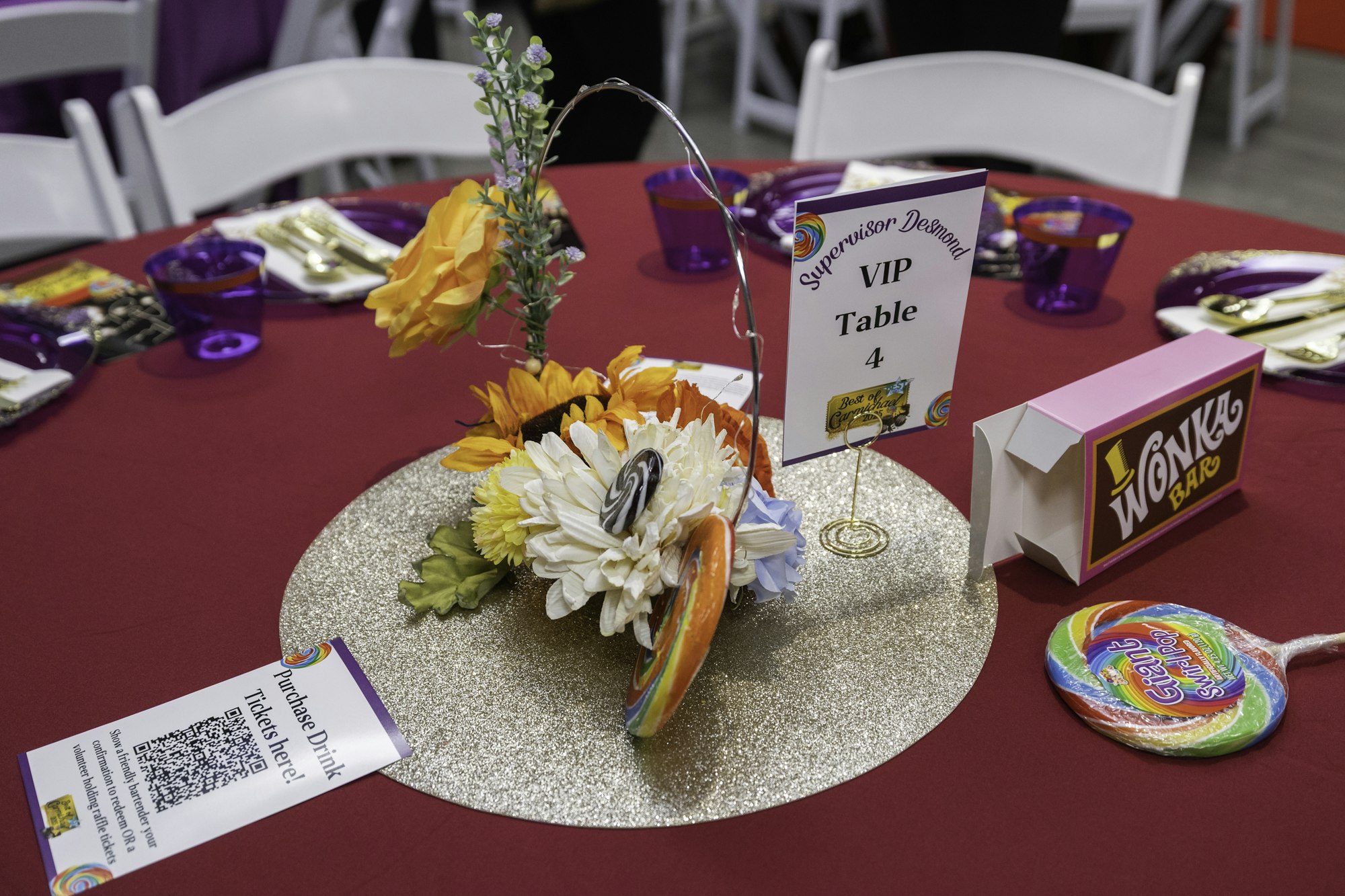 A decorated table with flowers, a lollipop, a "Wonka Bar" prop, and a sign labeled "VIP Table 4."