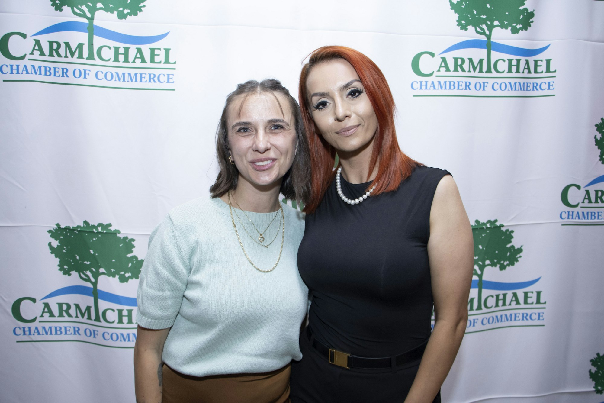 Two people posing in front of a Carmichael Chamber of Commerce backdrop.