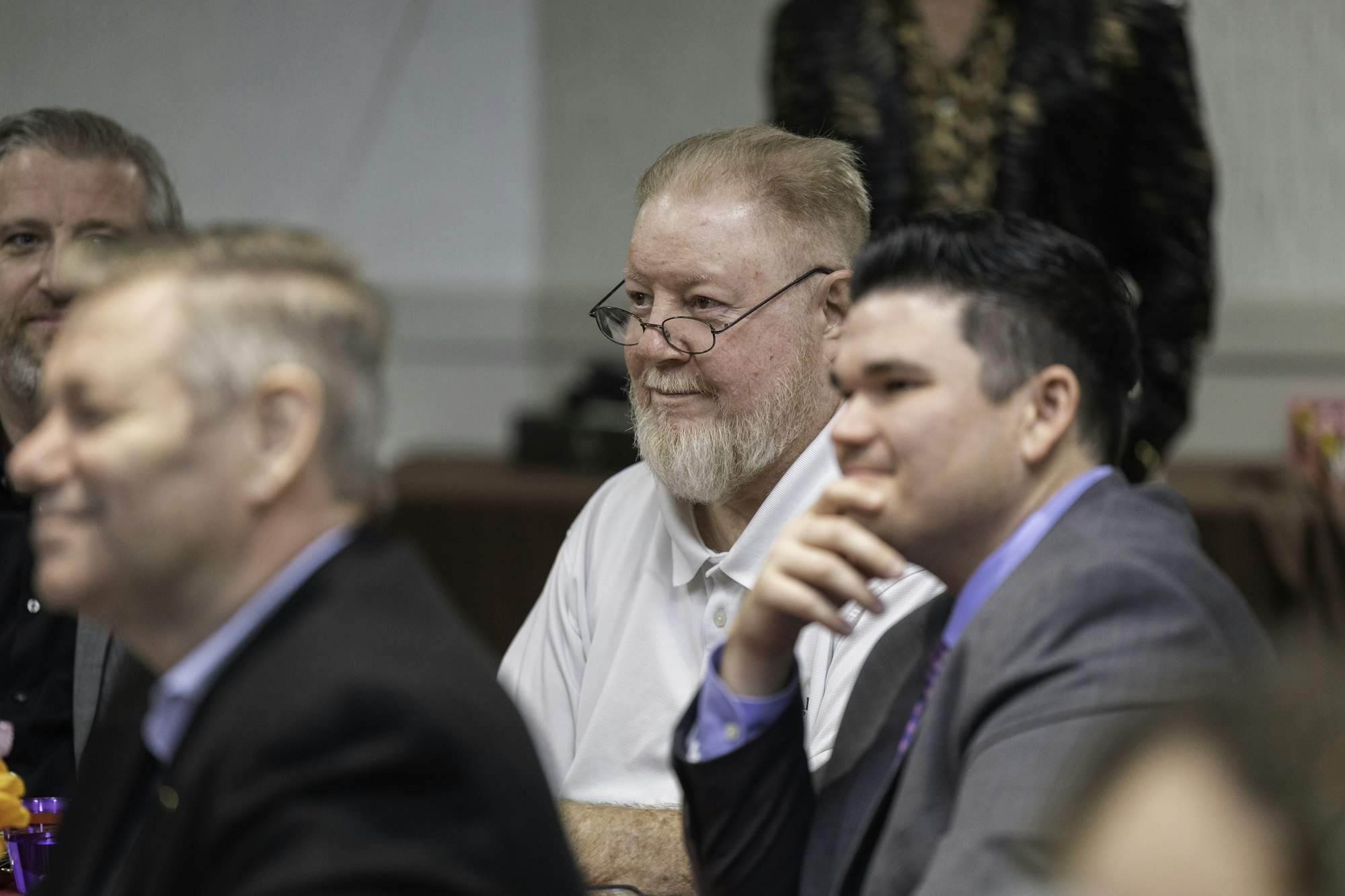 A group of people seated at a table, engaging in conversation or listening attentively.