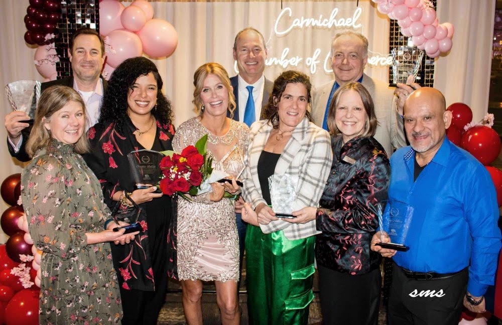 A group of people holding awards, standing in front of a backdrop with balloons and a "Chamber of Commerce" sign.
