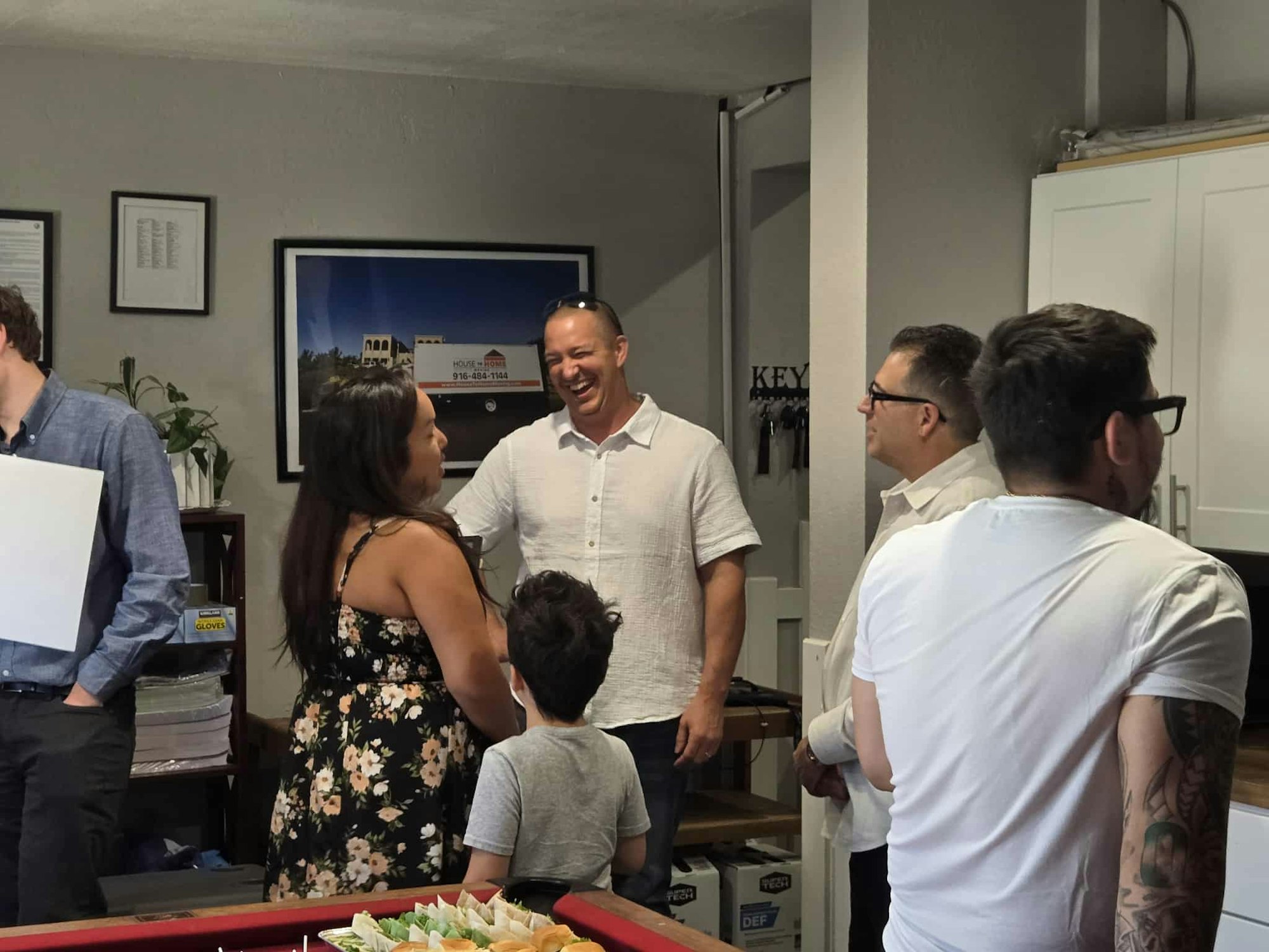 A group of people engaging in conversation indoors near a table with snacks.