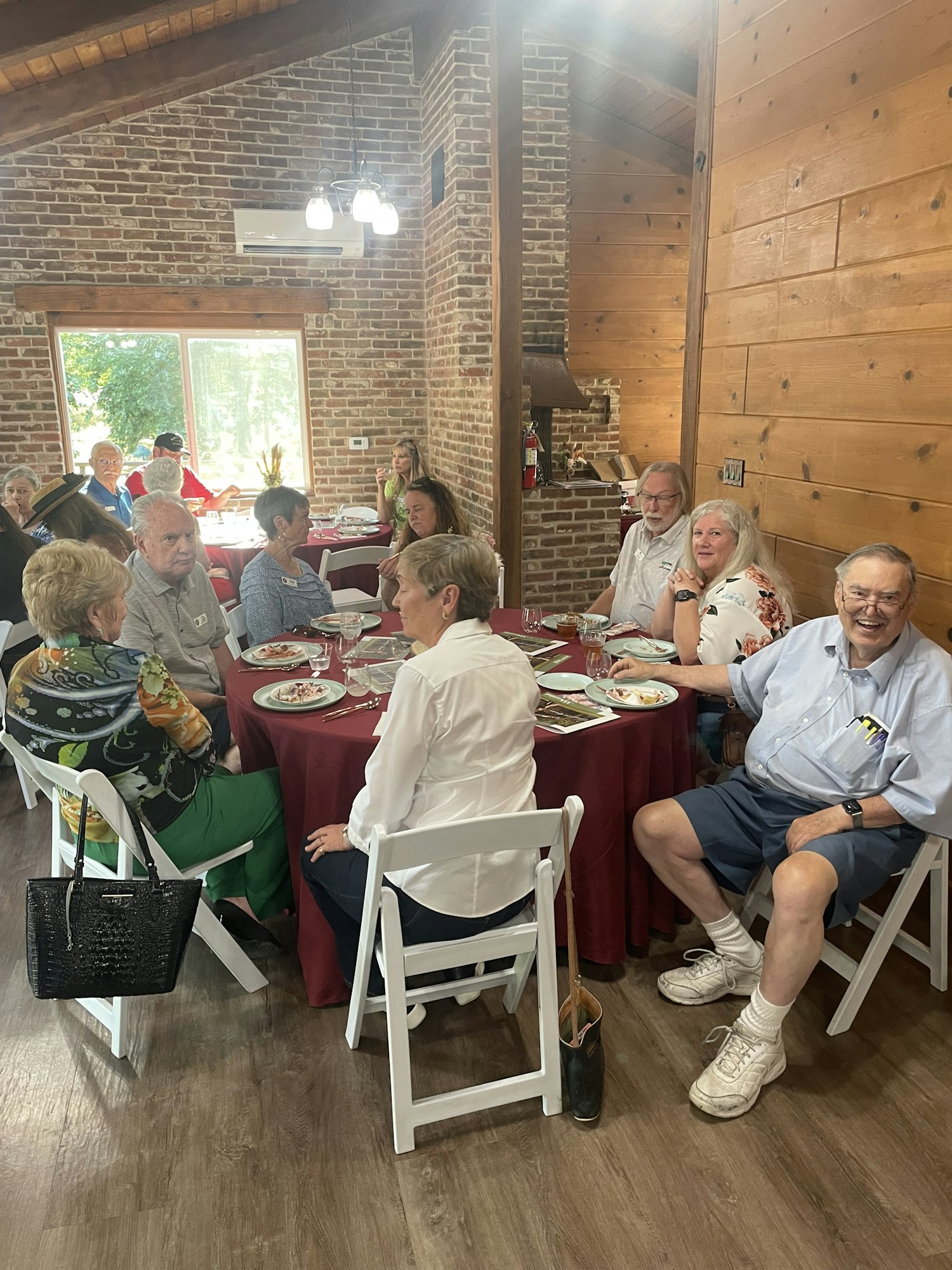 People sitting around a dining table inside a rustic room with wooden and brick walls, enjoying a meal.