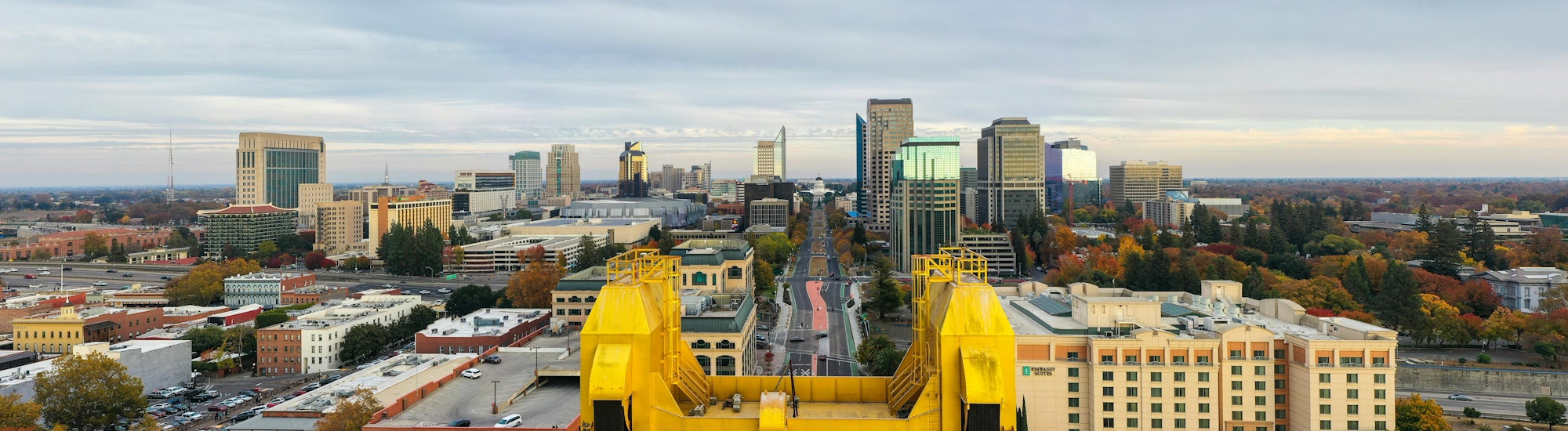 City skyline with various buildings and a prominent yellow bridge structure in the foreground.