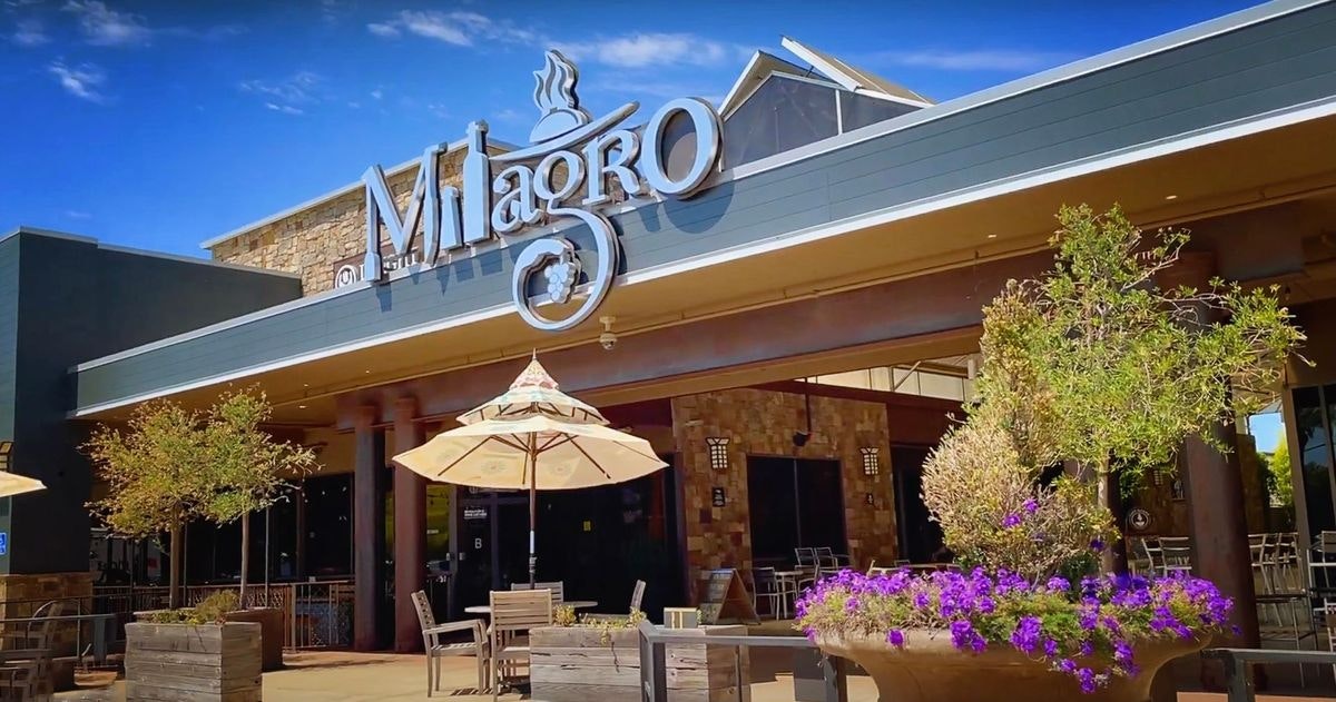 An exterior view of a restaurant named "Milagro" with outdoor seating and a sunny sky.