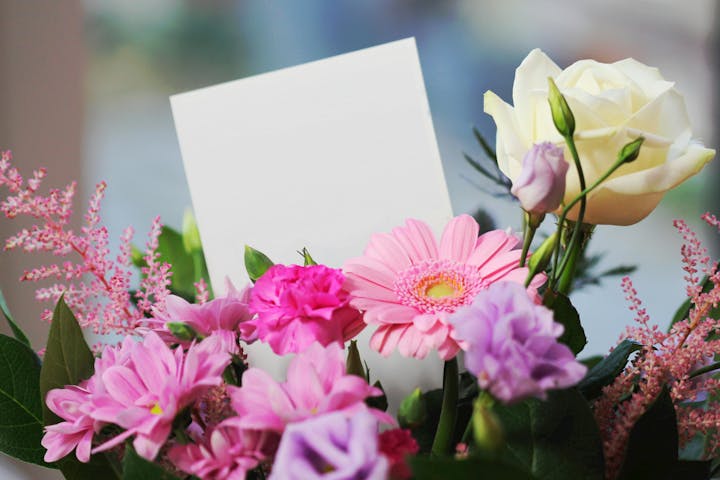 A bouquet of pink, purple, and white flowers with a blank card.