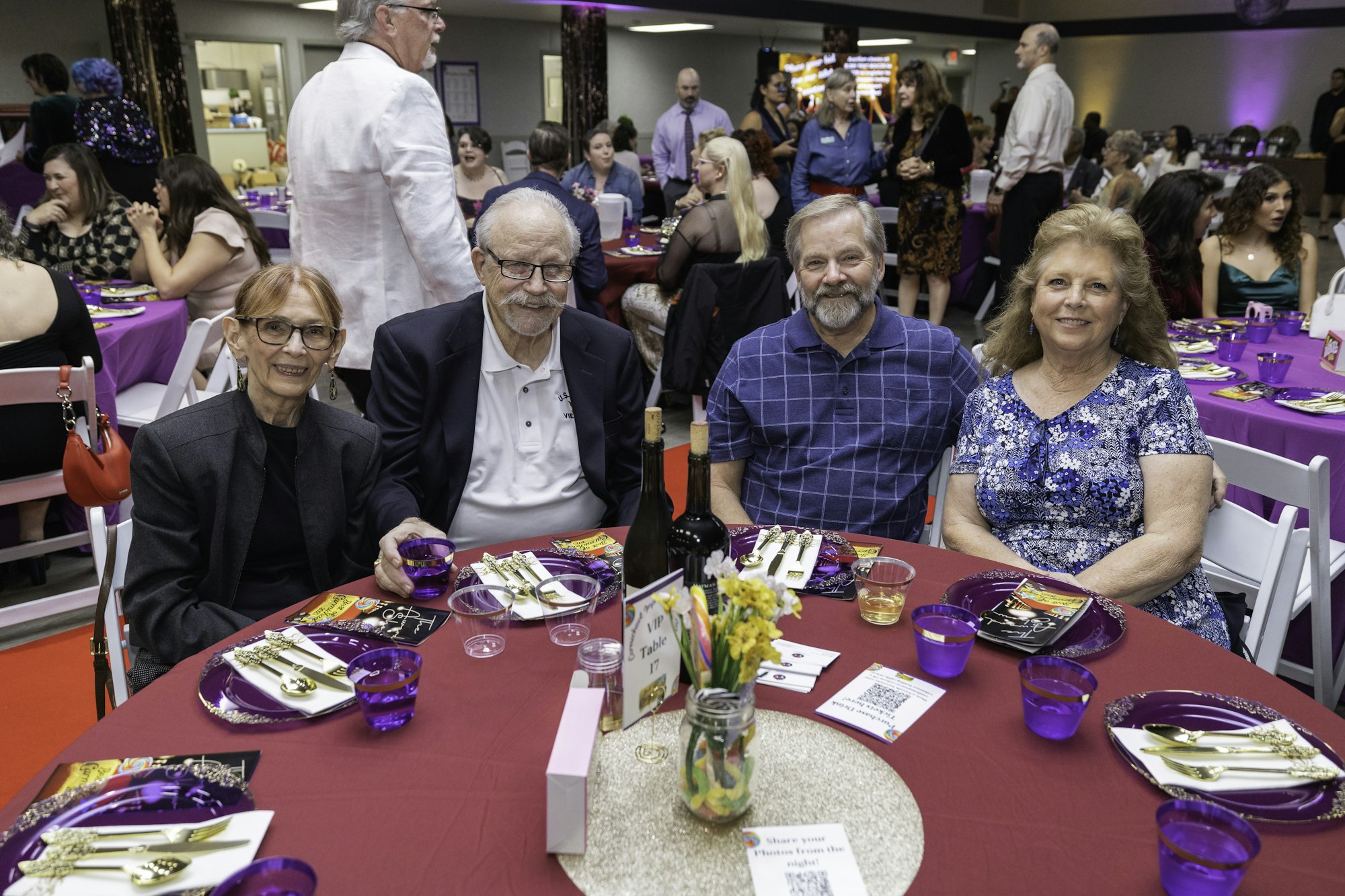 People seated at a table with purple decor at a formal event.