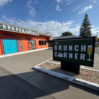 A restaurant called "The Brunch Corner" with outdoor signage and bright building under a blue sky.