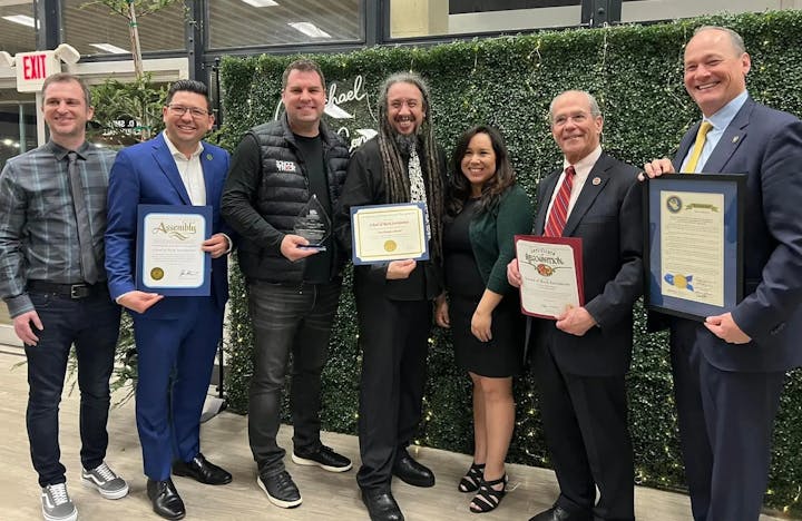 Group of people posing with awards/certificates, smiling for a photo.