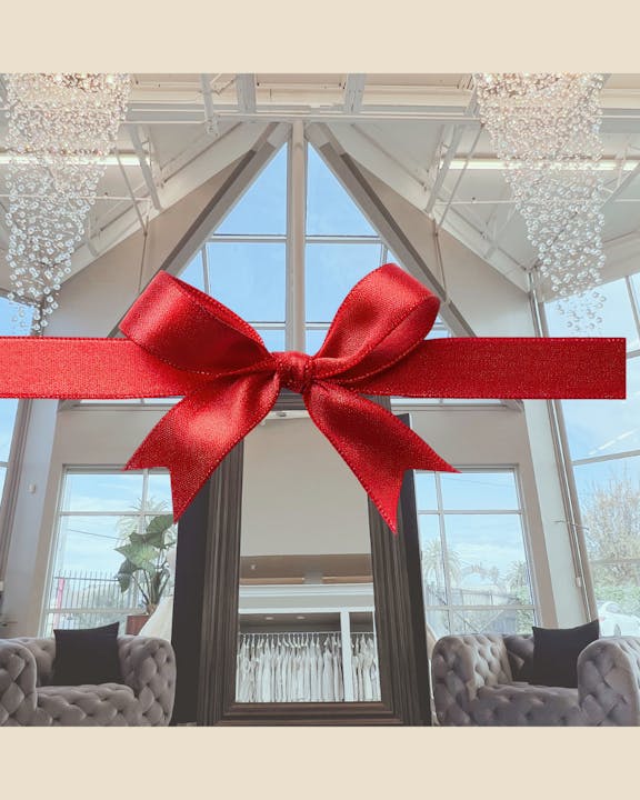 A bright interior featuring a large mirror, plush seating, and a decorative red bow across the center.