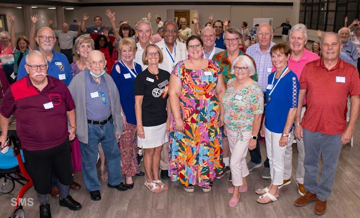 A group of smiling adults wearing name tags posing for a photo in an indoor setting.