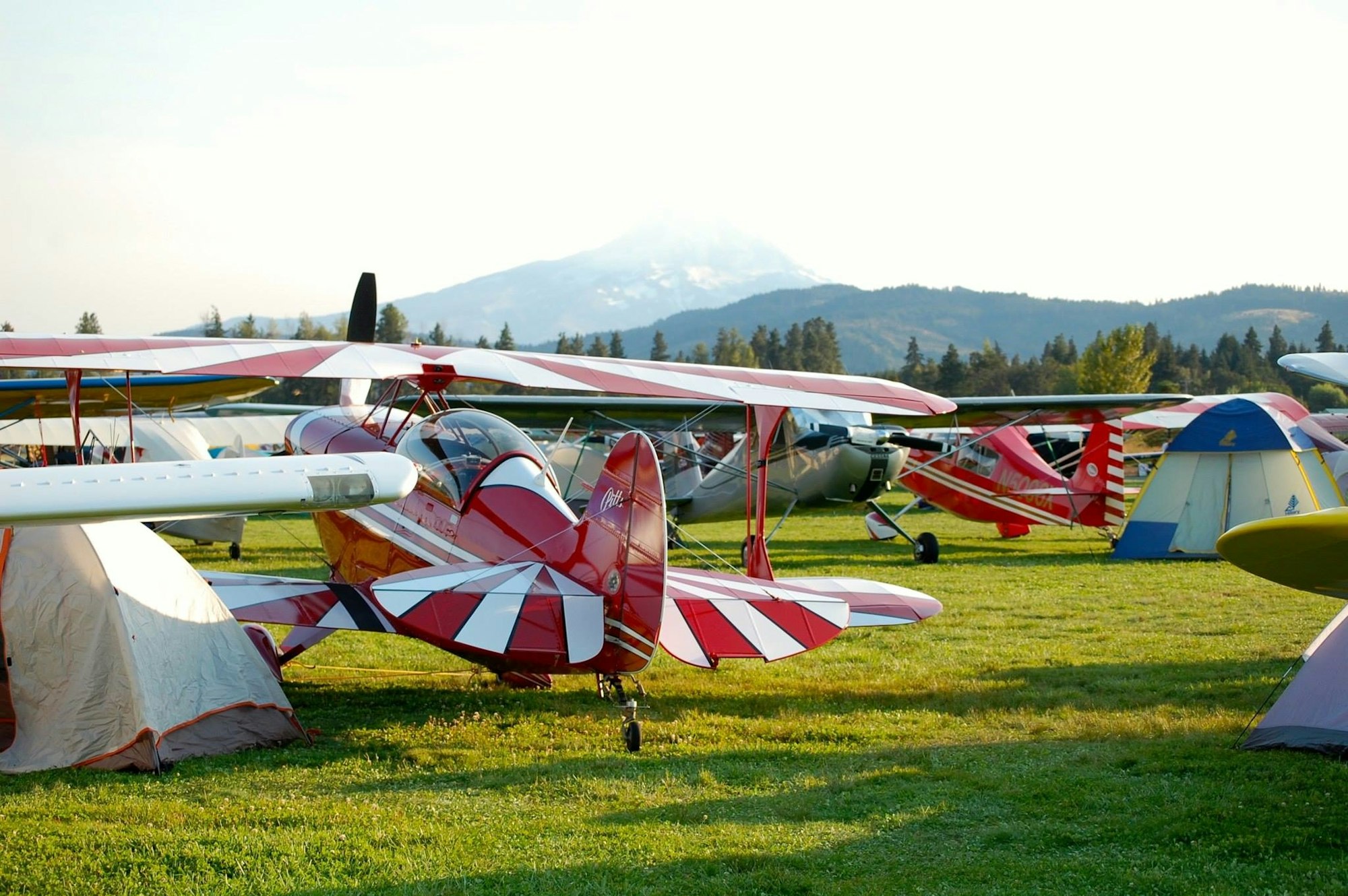 Small aircraft parked on grass with a mountain in the background.