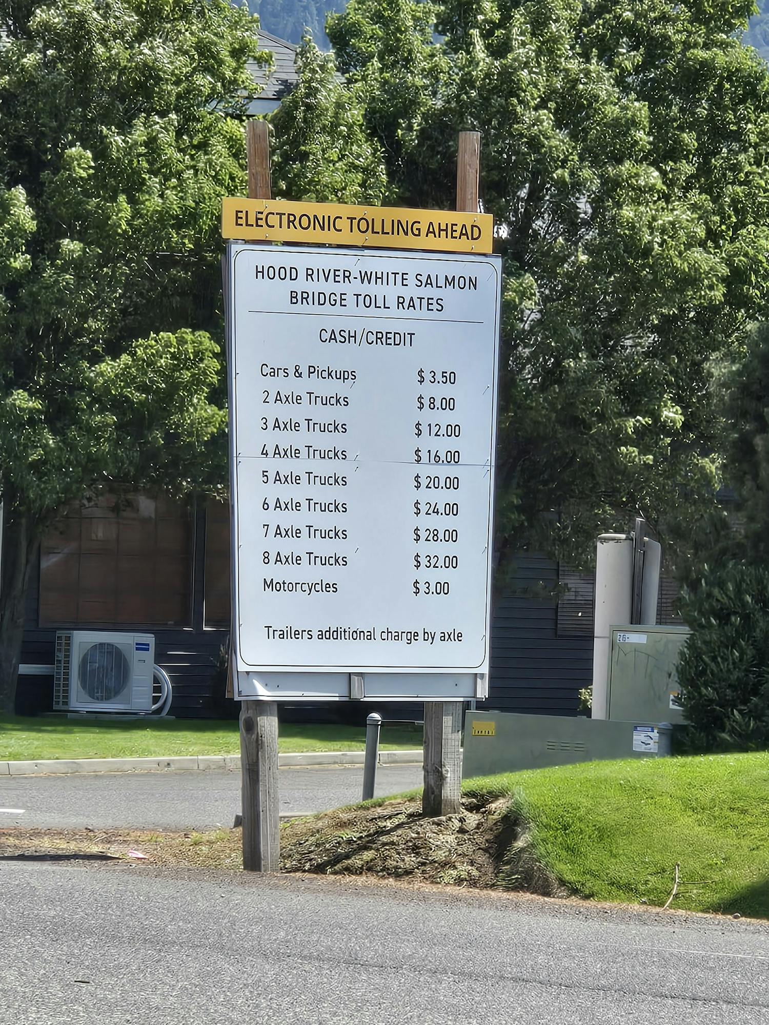 The image shows a toll sign with rates for different vehicle types at Hood River/White Salmon Bridge, including cash and electronic payment options.