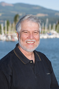 A smiling man with a harbor in the background.