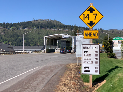 A weigh station with weight limit signs and a height warning ahead.