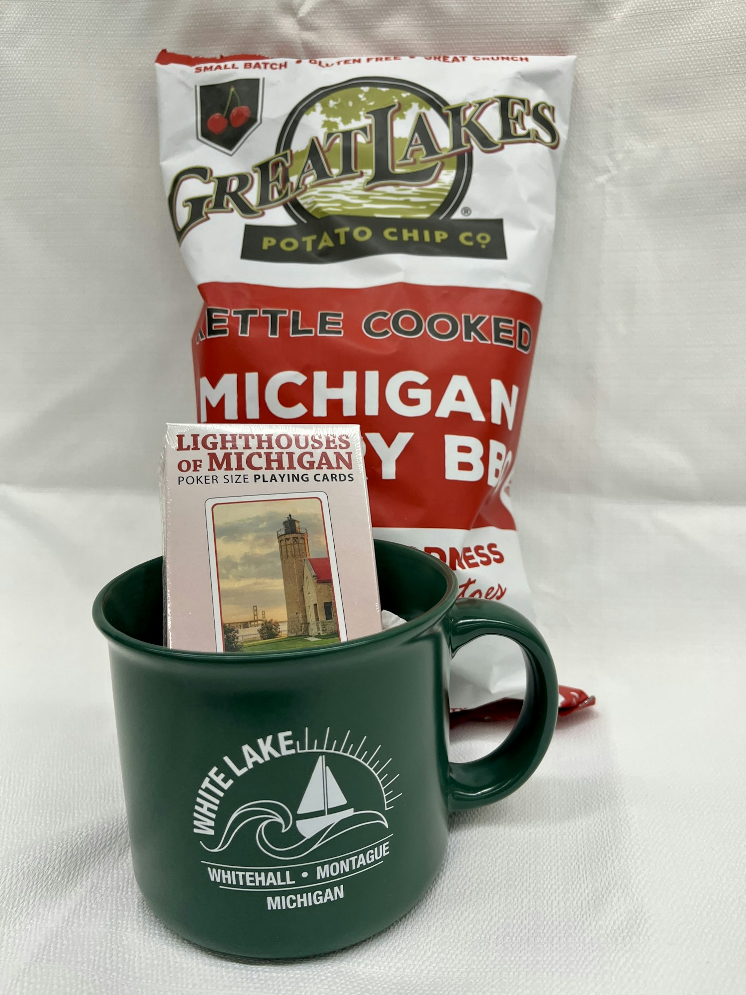 Bag of Michigan BBQ chips, a green White Lake Michigan mug, and Lighthouses of Michigan playing cards.