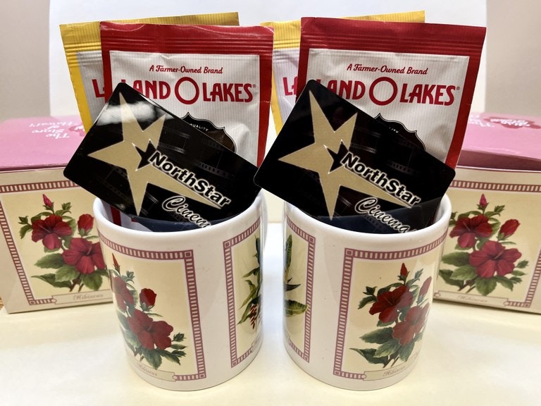 Two mugs with floral patterns containing packs of Land O'Lakes butter and Northstar cream. Boxes in background.